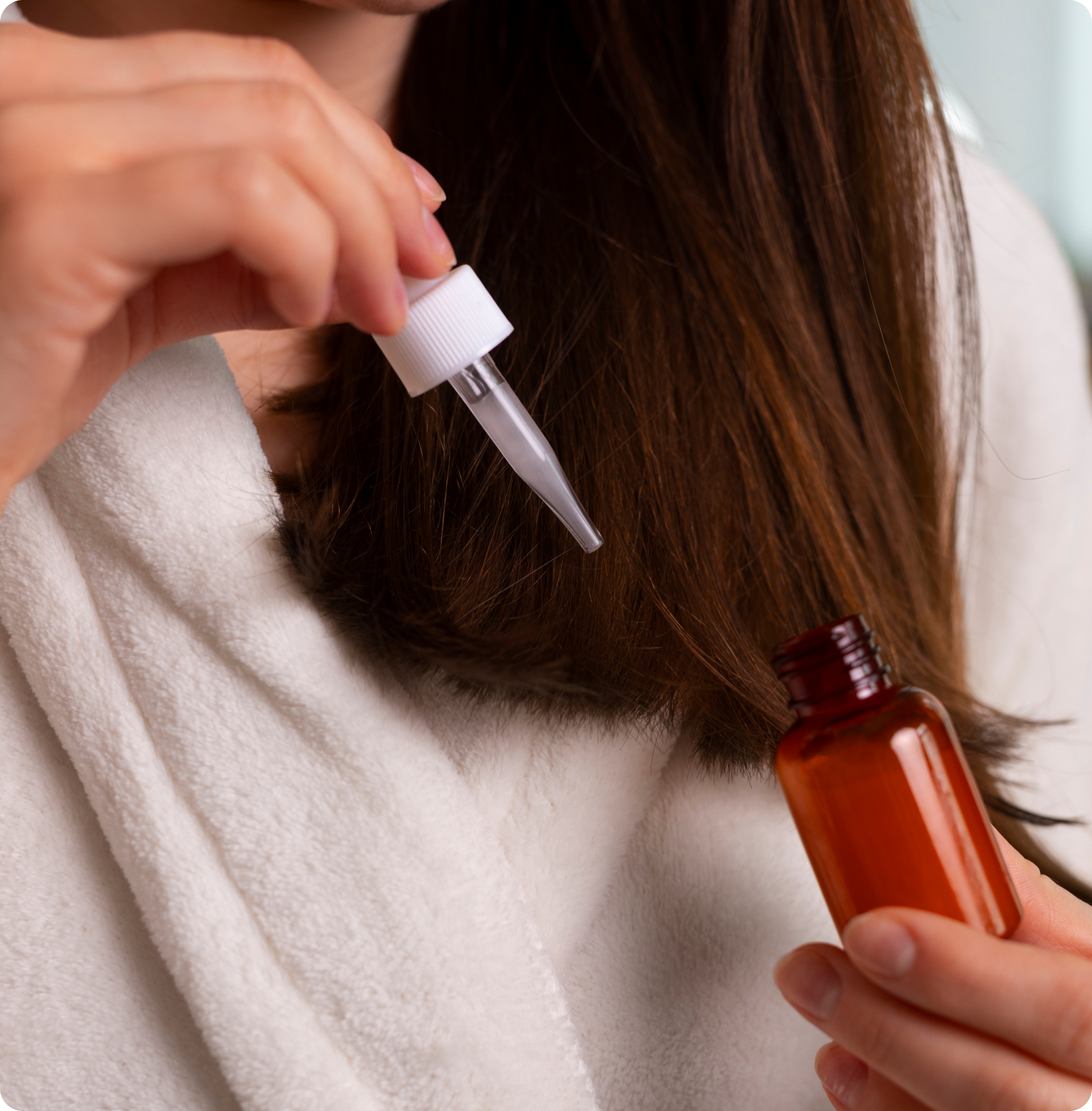 Hair treatment with a dropper applying liquid to the scalp near hairline.