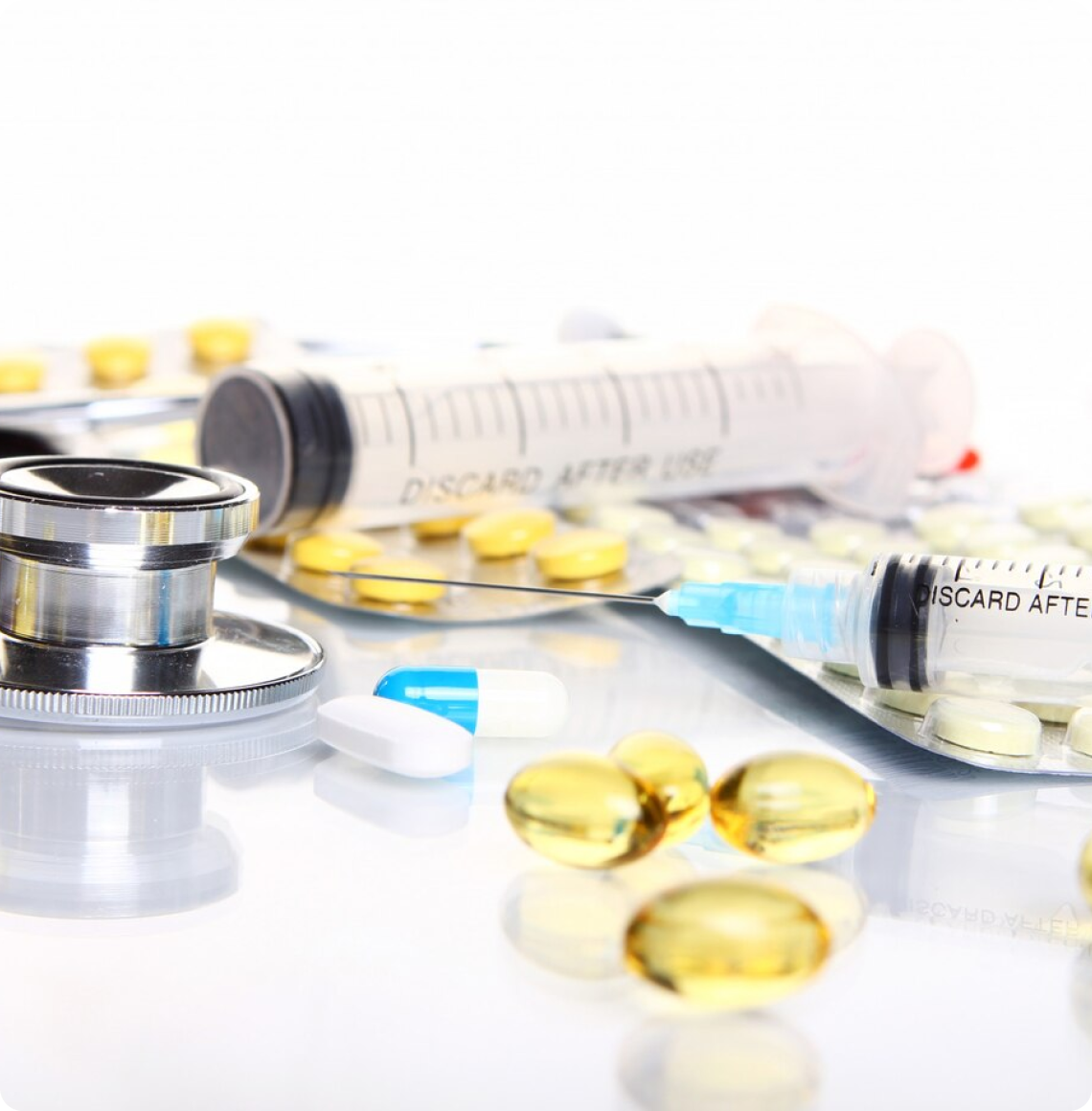 Medical supplies including pills, syringes, and a stethoscope on a white surface.