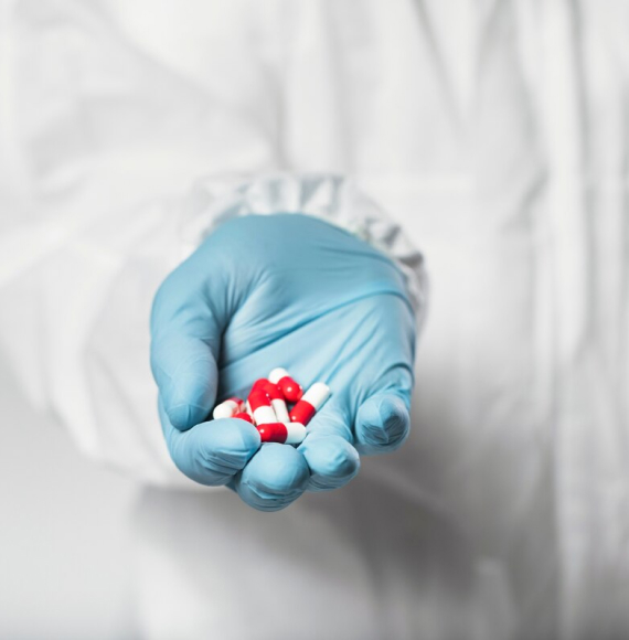 A gloved hand holding colorful capsule pills, symbolizing medication or pharmaceuticals.
