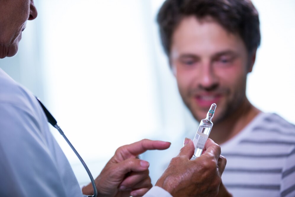 A doctor explains a vial of medication to a patient during a consultation.