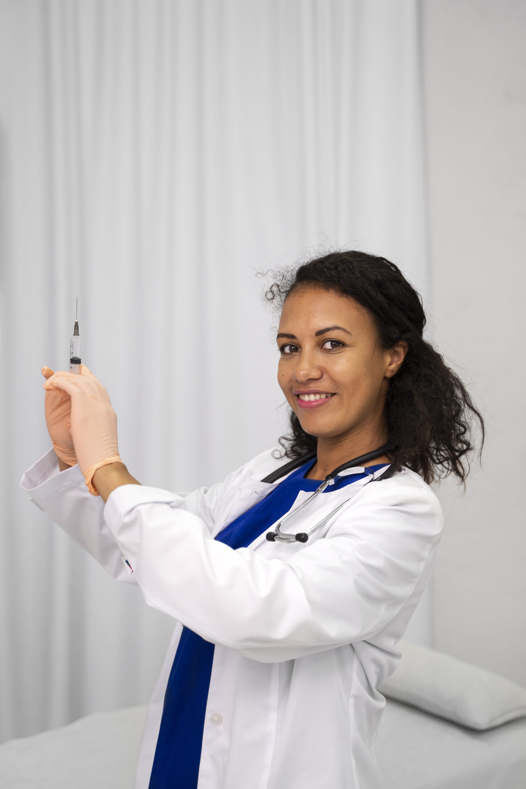 Medical professional holding syringe with gloved hand.