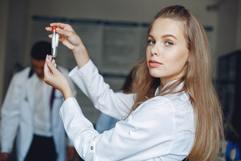 A young scientist in a lab coat holding a test tube over a Bunsen burner flame.