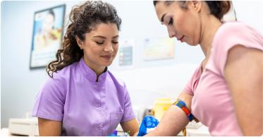 A healthcare professional assists a patient with a blood draw procedure.