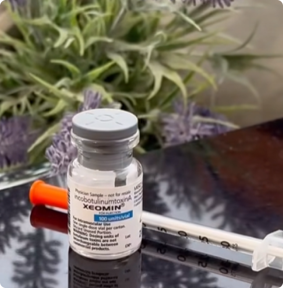 A vial of Xeomin (incobotulinumtoxinA) with syringe and orange cap on a reflective surface.