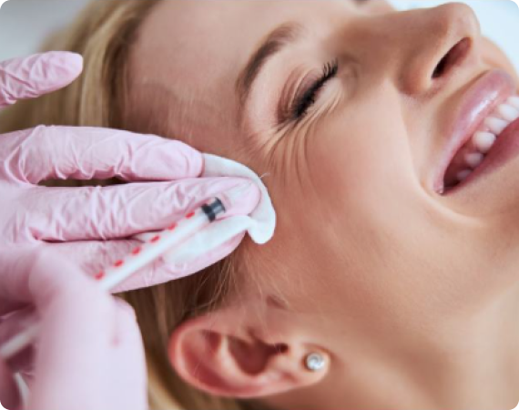 A professional administering a dermal filler injection near the cheekbone area.
