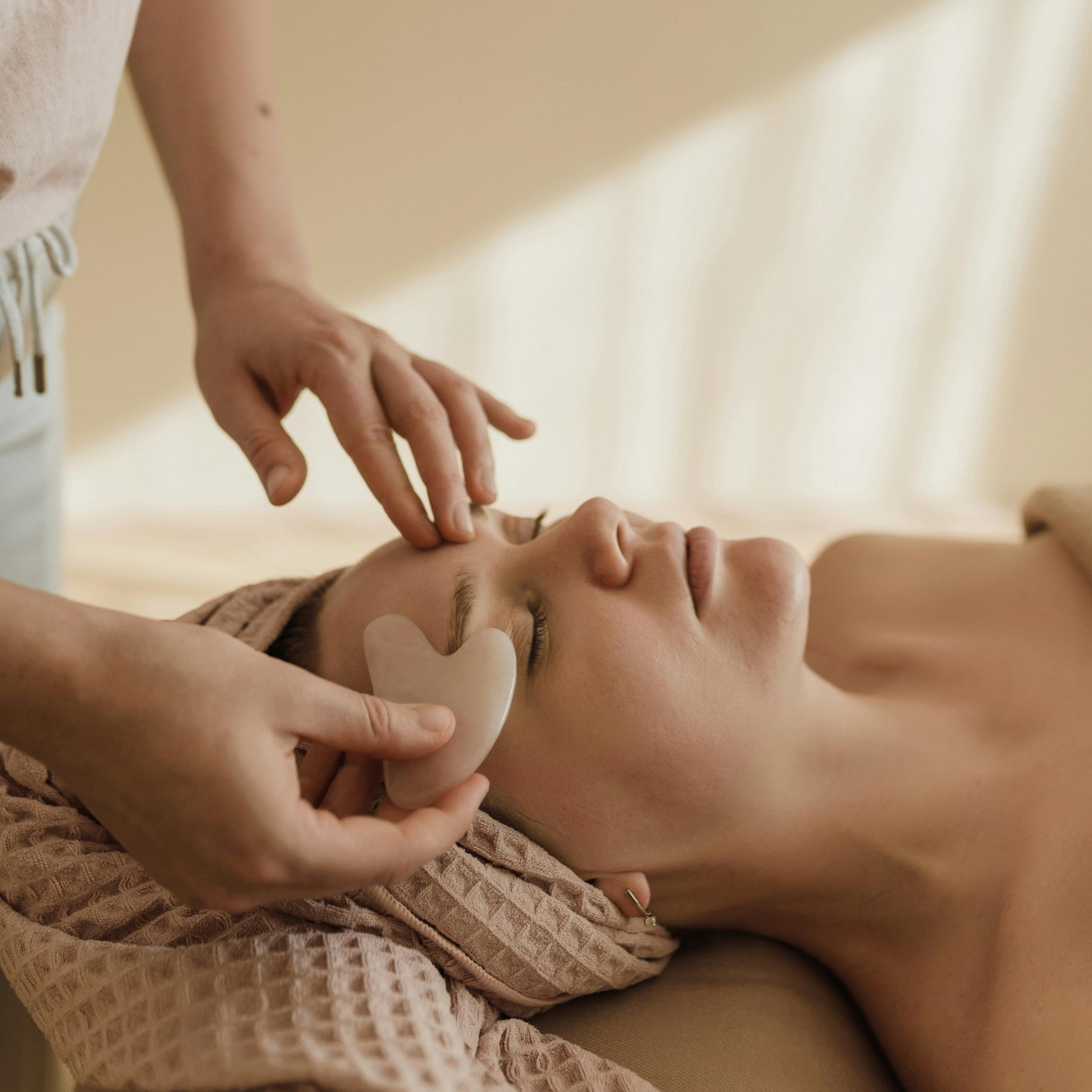 Hands performing acupressure on a person’s face and neck area.
